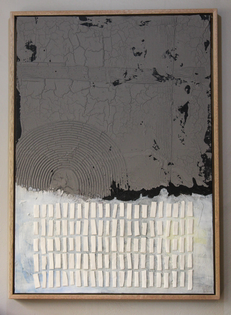 This mixed-media artwork contrasts a rugged, cracked upper half in deep charcoal gray with a lighter, textured lower half in soft whites and pale blues. A quiet resilience—blending raw materiality with delicate balance.